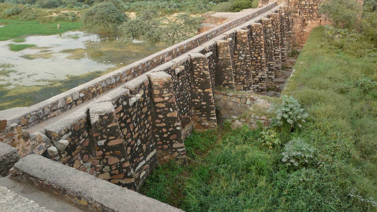 4. Satpula Dam | Dating back to the Tughlak dynasty, Satpula Dam is an ancient water-harvesting structure located near Khirki Village. This forgotten relic, once part of a complex irrigation system, showcases Delhi’s medieval engineering marvels. The name 'Satpula' refers to the seven bridges that originally supported the dam. Now a peaceful ruin, the dam offers a fascinating glimpse into the city’s ancient infrastructure and provides a serene spot for quiet reflection and exploration. (Image: Wikipedia)