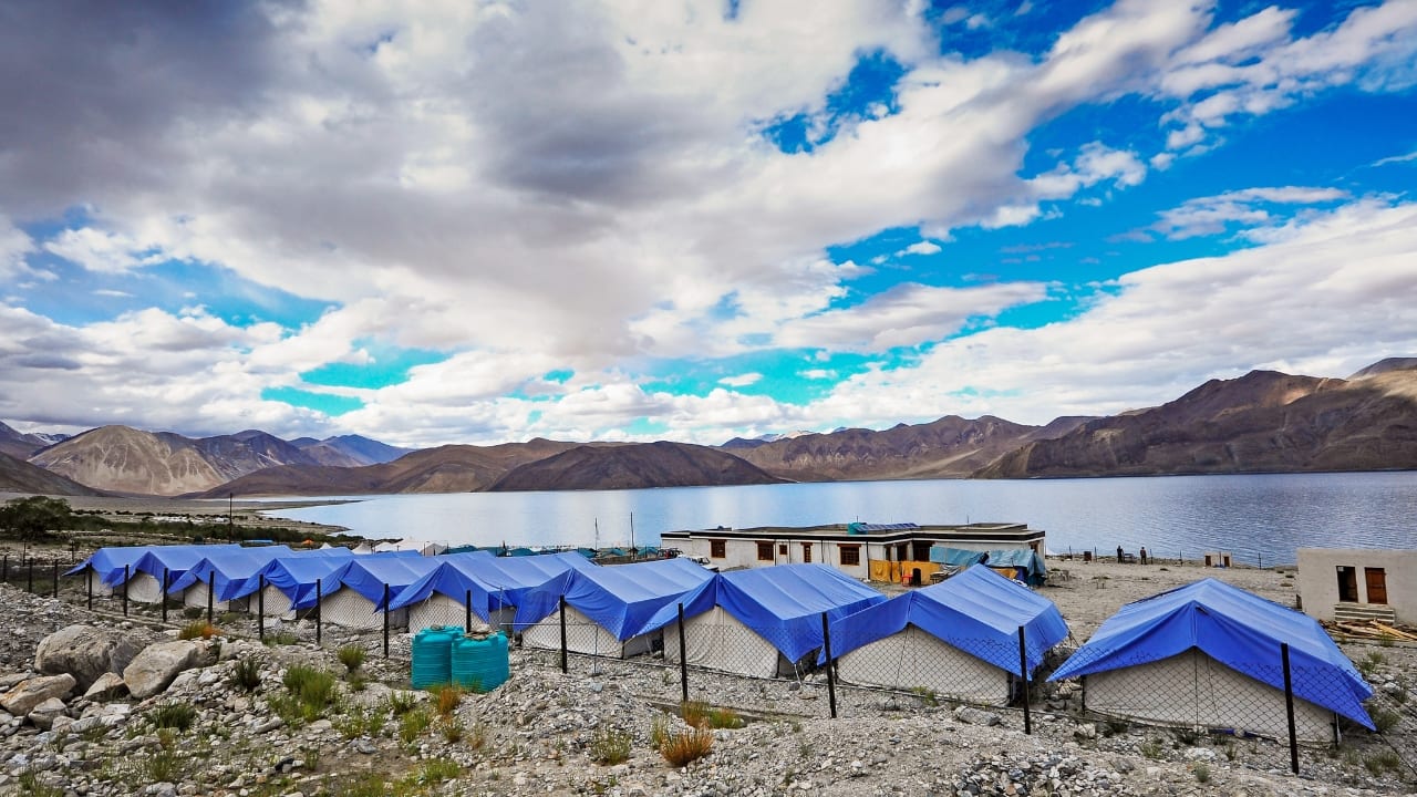 9. Pangong Lake, Ladakh: Lakeside Camping Like No Other Pangong Lake, with its ever-changing shades of blue, is one of the most mesmerizing camping destinations in India. At a height of 14,000 feet, this high-altitude lake offers a peaceful yet thrilling camping experience. The stark contrast between the deep blue lake and the rugged mountains makes for an otherworldly sight. Enjoy the silence and isolation, as the remote beauty of Pangong transports you to another world. (Image: Canva)