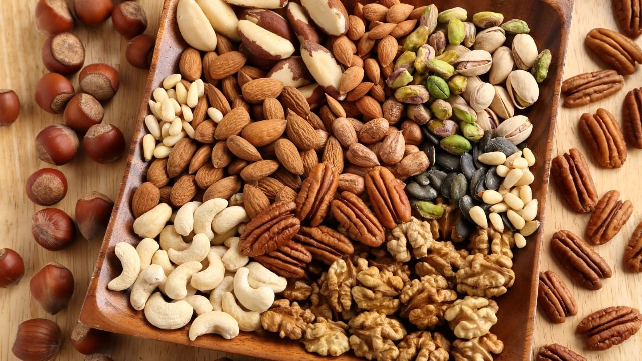 Nuts: Almonds, walnuts, and other nuts are rich in unsaturated fats, fibre, and plant sterols, which can help lower LDL cholesterol. Consuming a handful of nuts as a snack or adding them to salads and yoghurt can be beneficial. Nuts are also a good source of protein and can help keep you full, reducing the likelihood of snacking on less healthy options. (Image: Canva)