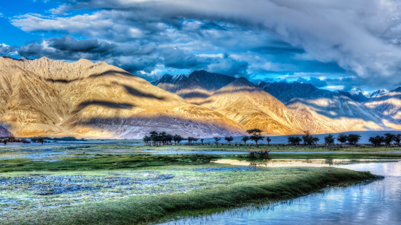 Desert dunes meet lush oases in this surreal landscape with Tibetan cultural influence. (Image: Canva)