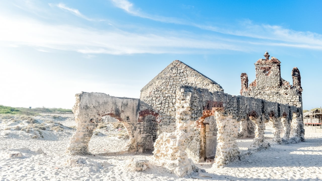 8. Dhanushkodi, Tamil Nadu Dhanushkodi, a ghost town near the India-Sri Lanka border, is an intriguing destination for history buffs and adventure seekers alike. Once a thriving town, Dhanushkodi now stands as a silent testament to time, with the remnants of its old structures scattered along its desolate beaches. A visit to Dhanushkodi also offers views of the Adam’s Bridge (Rama Setu), a mythical structure that adds to the destination's intrigue. (Image: Canva)