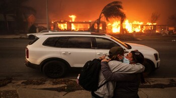 People embrace as they evacuate following powerful winds fueling devastating wildfires in the Los Angeles area, at the Eaton Fire in Altadena, California, U.S. January 8, 2025. REUTERS/David Swanson