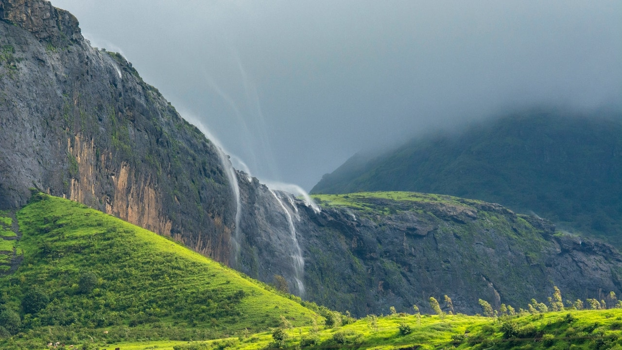 1. Naneghat Reverse Waterfall Location: Maharashtra, India The Naneghat Reverse Waterfall in Maharashtra stands out as a remarkable sight. The water seems to move up instead of down creating an optical trick. This happens because strong winds push the water back making it look like it's going against gravity. To see it at its best, go there during the rainy months (June–September). (Image: Canva)