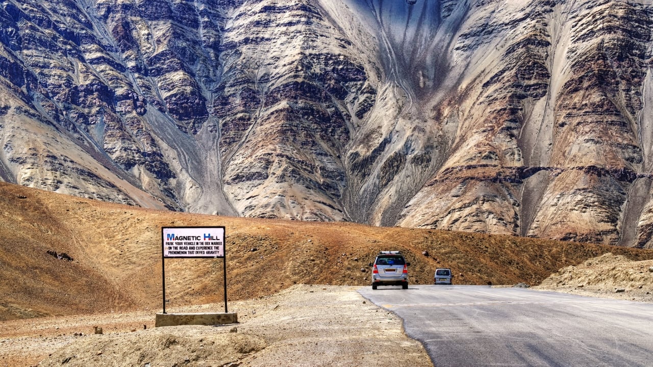3. Magnetic Hill Location: Ladakh, India Magnetic Hill in Ladakh ranks among the world's most well-known anti-gravity locations making it a spot travelers shouldn't miss. At this site, cars seem to move uphill by themselves, without any outside push. The secret behind this strange sight comes from an optical trick. The landscape around the hill fools our eyes making what's a downward slope look like it goes up. (Image: Canva)