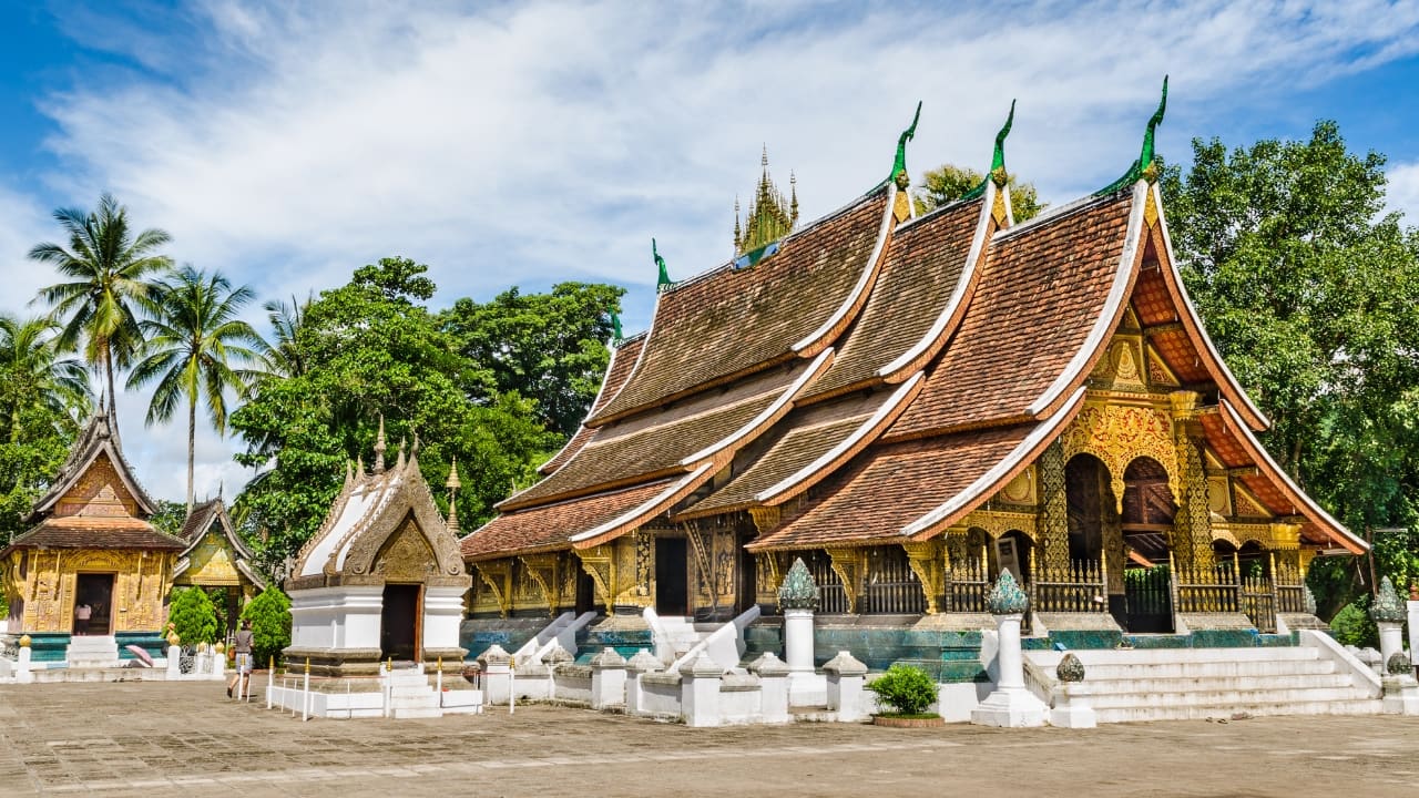 5. Wat Xieng Thong – The Jewel of Laos Location: Luang Prabang, Laos Nestled along the Mekong River in Luang Prabang, Wat Xieng Thong is a masterpiece of traditional Lao architecture. Its sweeping tiered roofs, intricate gold stencils, and the famous &quot;Tree of Life&quot; mosaic make it a must-see for culture enthusiasts. This serene temple complex provides a peaceful setting to experience Buddhist traditions and admire Laos' unique craftsmanship. (Image: Canva)