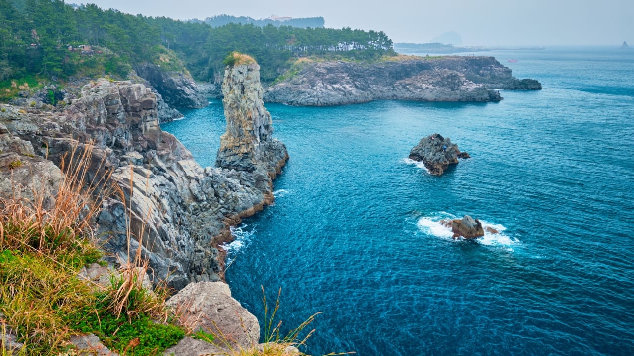 10. Jeju Island – The Ultimate K-Drama Escape Jeju Island is a paradise that has set the stage for countless romantic K-dramas. From volcanic landscapes to serene beaches, it’s the ultimate getaway for any fan looking to escape into a dreamy K-drama world. Walk through the scenic fields from Warm and Cozy, or visit the picturesque spots from Secret Garden. Must-Do: Visit Jeju’s famous café scenes and sip coffee with a view, just like in your favorite dramas. (Image: Canva)