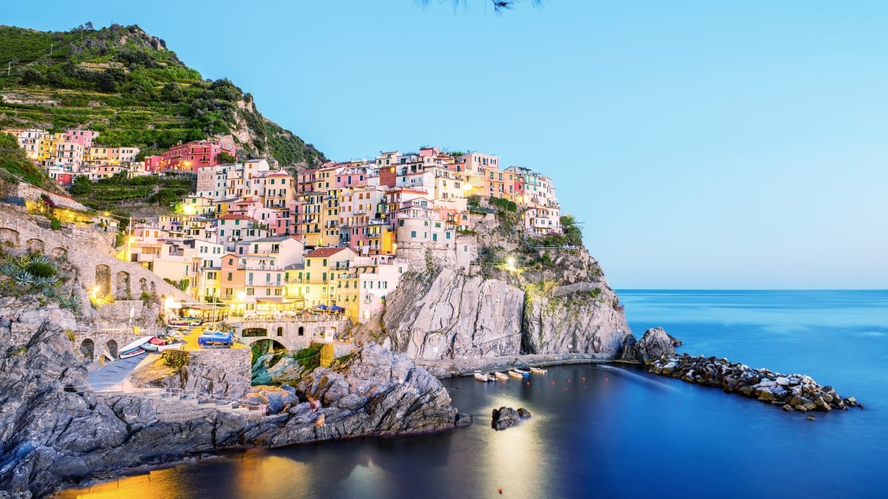 10. Bid Farewell to the Amalfi Coast by Seeing Cinque Terre. Though the Amalfi Coast is breathtaking, it has evolved into a tourist trap. Conversely, Cinque Terre is a more sedate, romantic coastal area of Italy. Perched along the Ligurian Sea, the five vibrant towns offer a slower pace, spectacular cliffs, and amazing vistas. See the breathtaking scenery around you in this magical part of Italy, hike amongst the villages, and sip wine in a cliffside restaurant. (Image: Canva)