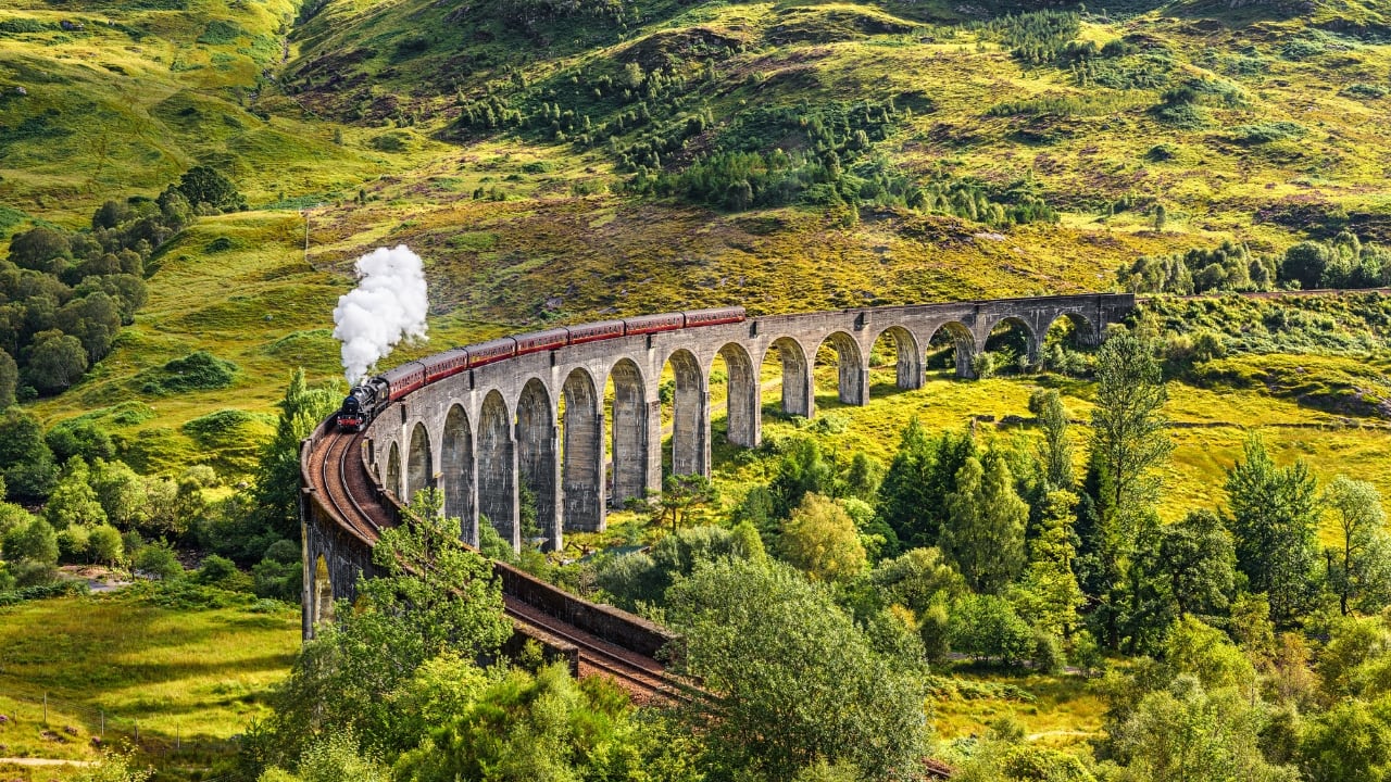 5. Ride the Real Hogwarts Express from Fort William to Mallaig Location: Scotland Traveling across the famous Glenfinnan Viaduct—the same railway bridge the Hogwarts Express passes in the movies—the Jacobite Steam Train carries people over the magnificent Scottish Highlands. The trip is just as enchanted as the destination, with rolling green vistas, misty mountains, and glistening lochs. (Image: Canva)