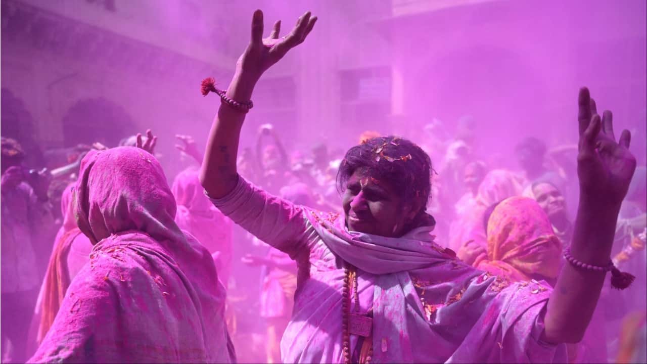 Widows smeared with gulal dance as they celebrate Holi at a temple in Vrindavan on Wednesday. (Image credit: AFP)