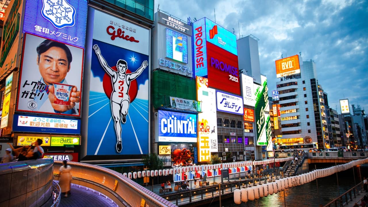 1. Dive into the Neon Magic of Dotonbori Dotonbori isn’t just a street—it’s an experience. Picture neon billboards lighting up the night, the scent of sizzling street food, and crowds soaking in the energy. Don’t miss out on takoyaki (octopus balls) and a photo with the famous Glico running man—a classic Osaka moment! (Image: Canva)