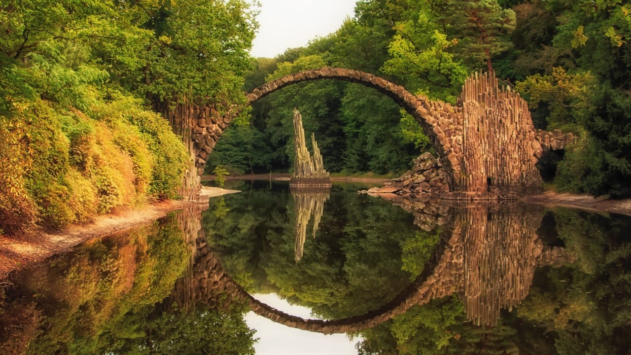 5. Rakotzbrücke (The Devil’s Bridge) – Germany’s Perfect Circle Deep in the forests of Germany lies a bridge that looks like something out of a fairytale. Rakotzbrücke, built in the 19th century, forms a perfect circle when its reflection meets the water below. Local legends claim the devil himself built it—after all, how else could something so impossibly precise exist? This illusion is a reminder that some places feel too magical to be real. (Image: Canva)
