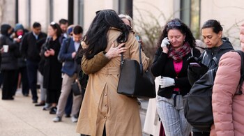 Employees of the Department of Health and Human Services (HHS) hug each other as they queue outside the Mary E. Switzer Memorial Building, after it was reported that the Trump administration fired staff at the Centers for Disease Control and Prevention and at the Food and Drug Administration, as it embarked on its plan to cut 10,000 jobs at HHS, in Washington, D.C., U.S., April 1, 2025. REUTERS/Kevin Lamarque