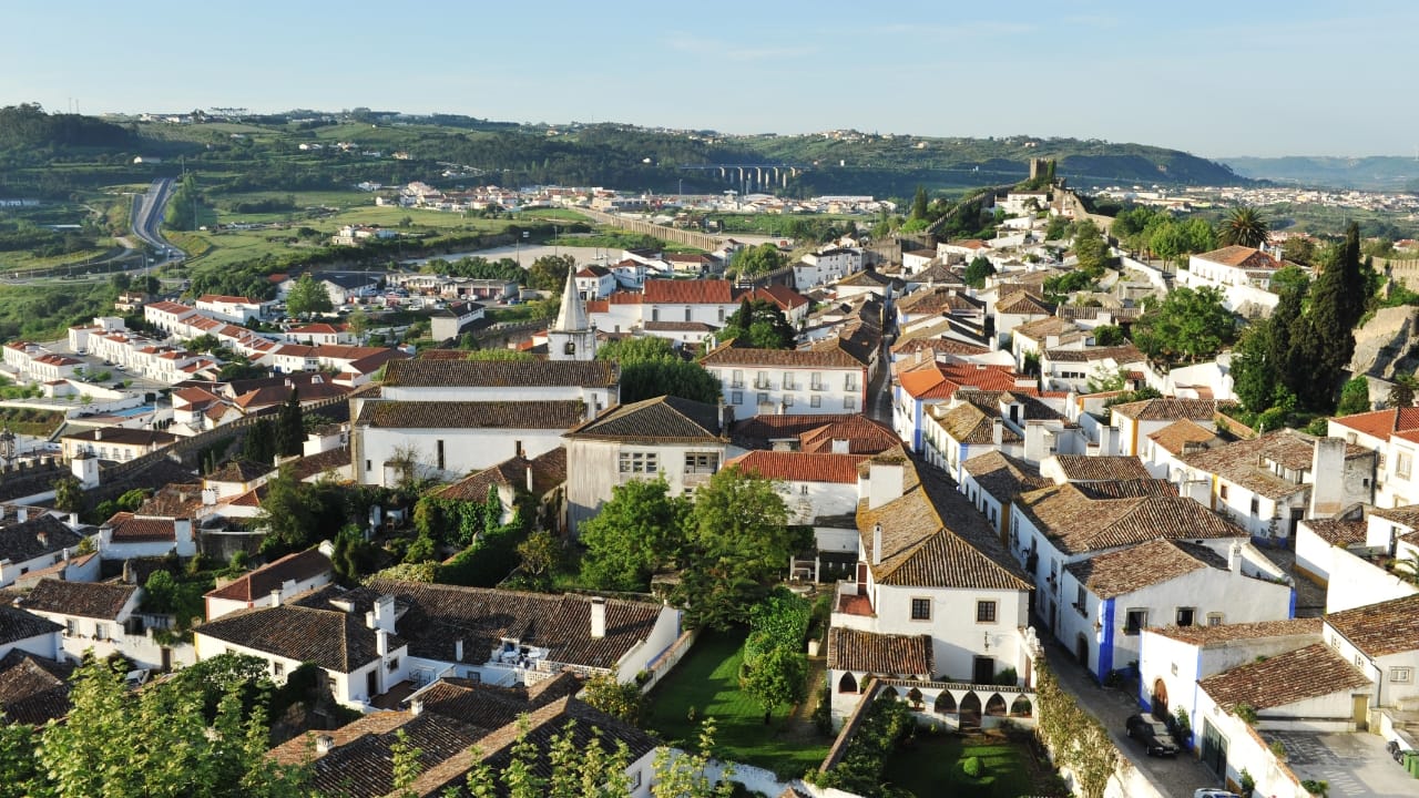 2. Óbidos, Portugal – Books in a Castle, Anyone? Imagine strolling through a 12th-century walled town, where chapels, markets, and even wine cellars double as bookstores. That’s Óbidos. This Portuguese gem has transformed into a magical book town where literature seeps out of every medieval nook. (Image: Canva)