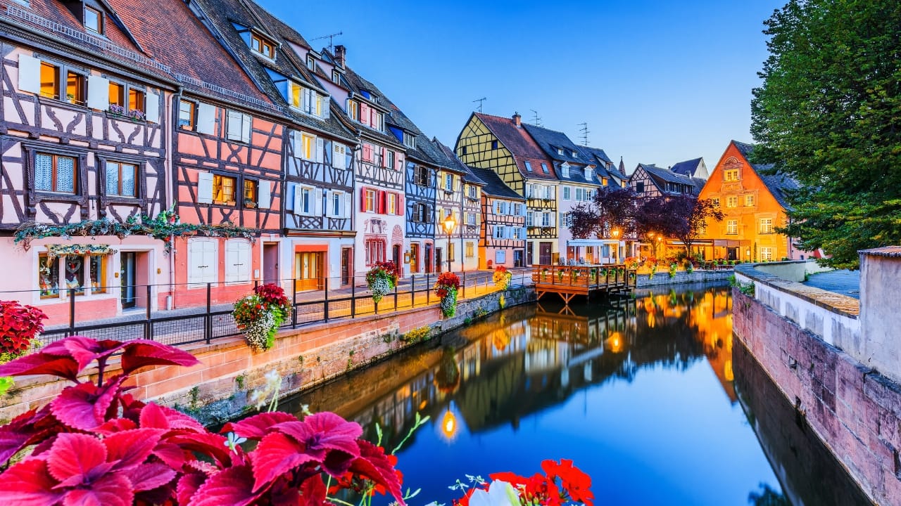 6. Colmar, France Colmar looks like it’s straight out of a fairy tale, and with its colorful timbered houses, flower-lined canals, and cobbled streets, it’s easy to see why. Located in the Alsace region, this picturesque town boasts hues so vibrant that even the flowers seem to compete with the buildings. It’s the kind of place that feels magical at every turn. (Image: Canva)
