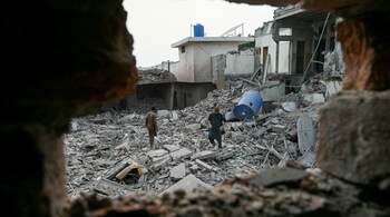 Locals stand on the debris of destroyed structures in Muridke about 30 kilometres from Lahore, on May 7, after Indian strikes.