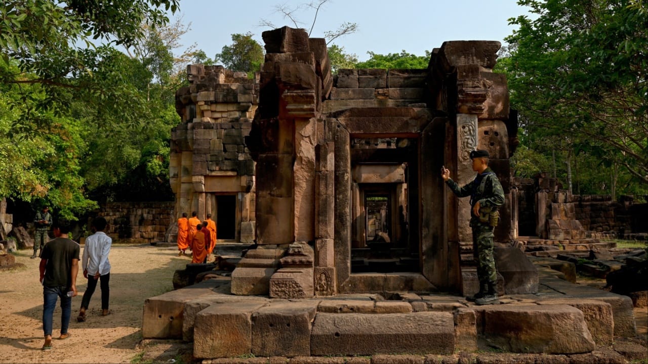 A Thai soldier (R) takes pictures of Cambodian people visiting the disputed ancient Khmer temple Prasat Ta Muen Thom, or Prasat Ta Moan Thom in Khmer, on the Cambodian-Thai border in Oddar Meanchey province on March 26. (Image credit: AFP)