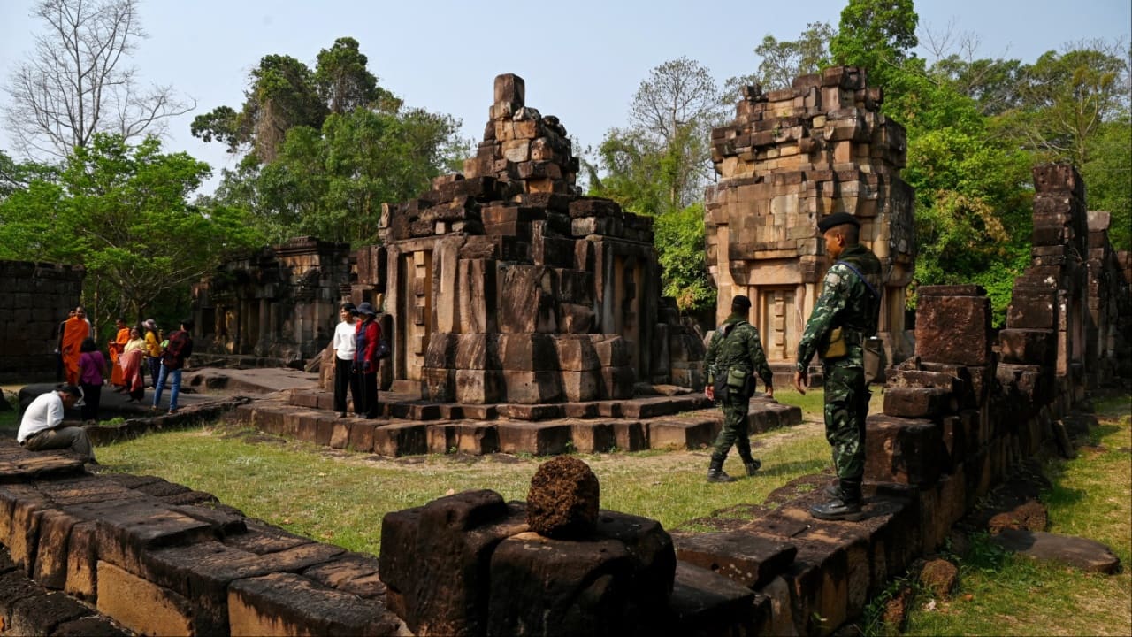 A Thai soldier stands guard as Cambodian people visit the disputed ancient Khmer temple Prasat Ta Muen Thom, or Prasat Ta Moan Thom in Khmer, on the Cambodian-Thai border in Oddar Meanchey province on March 26. (Image credit: AFP)