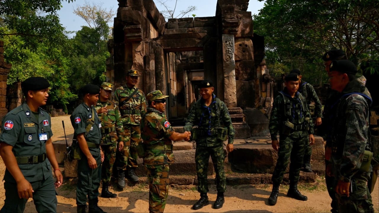 A Cambodian soldier (centre L) shakes hands with a Thai soldier (centre R) at the disputed ancient Khmer temple Prasat Ta Muen Thom, or Prasat Ta Moan Thom in Khmer, on the Cambodian-Thai border in Oddar Meanchey province on March 26. (Image credit: AFP)