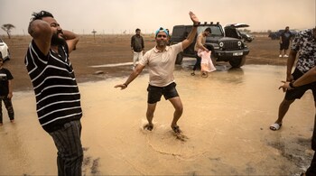 People stand in the rain during a 'rain chase' in the emirate of Sharjah. (Image credit: AFP)