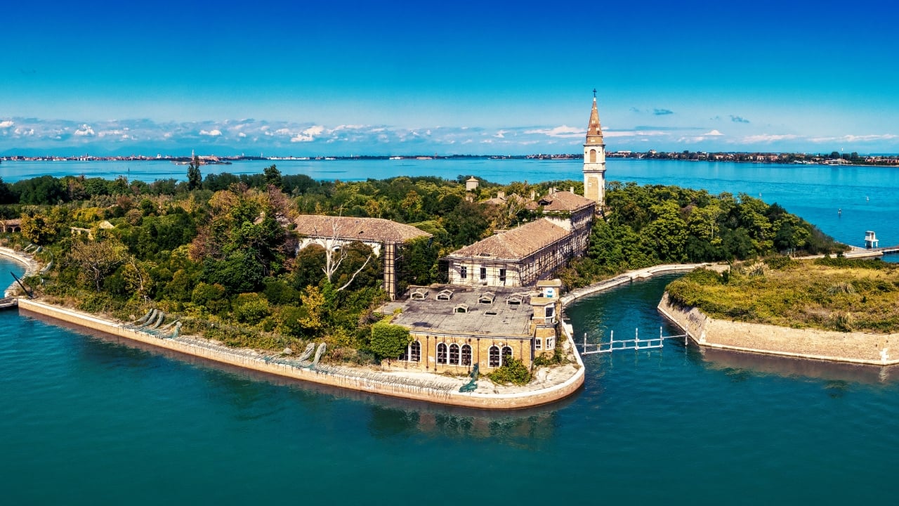 6. Poveglia Island, Venice Lagoon, Italy Few places carry a legacy as disturbing as Poveglia. Once a quarantine station for plague victims and later a mental asylum, the island’s haunting ruins remain closed to the public under Italian law. Although ghost stories abound, the real danger lies in decaying buildings and collapsed floors. It is a place where history has not faded—it has curdled. (Image: Canva)