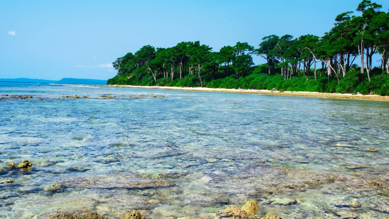 8. Kalapathar Beach – Havelock Island, Andaman &amp; Nicobar Named for the dark rocks that line its edge, Kalapathar is less visited, more quiet. The contrast of inky stone and aquamarine surf feels cinematic. Come early, stay late. Time here does not pass—it pauses. (Image: Canva)