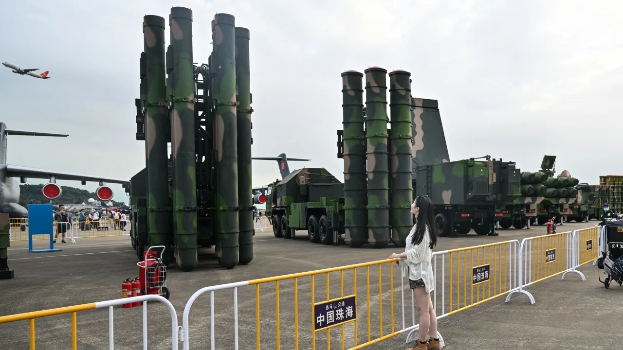 A woman poses for pictures next to the HQ-9B surface-to-air missile system (L) and the HQ-19 surface-to-air missile system during the 15th China International Aviation and Aerospace Exhibition in Zhuhai, in southern China's Guangdong province on November 15, 2024. (Photo by Hector RETAMAL / AFP)
