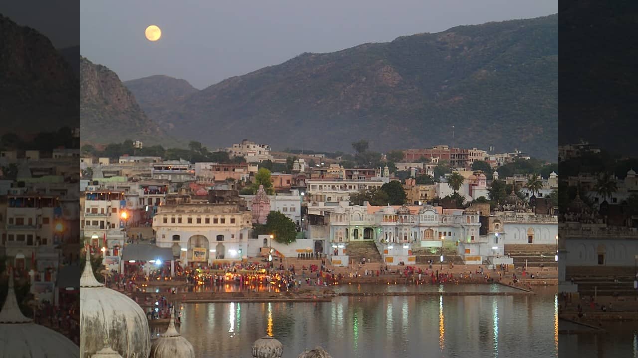 2. Pushkar – Rajasthan Pushkar is no stranger to spectacle, but when the full moon casts its silver light over the holy lake, the town exudes a peculiar stillness. Temple bells echo longer. The water glows faintly. During the Kartik Purnima fair, the scene transforms into something between pilgrimage and theatre, with camels, chants, and a thousand lanterns dancing on the breeze. (Image: Wikipedia)