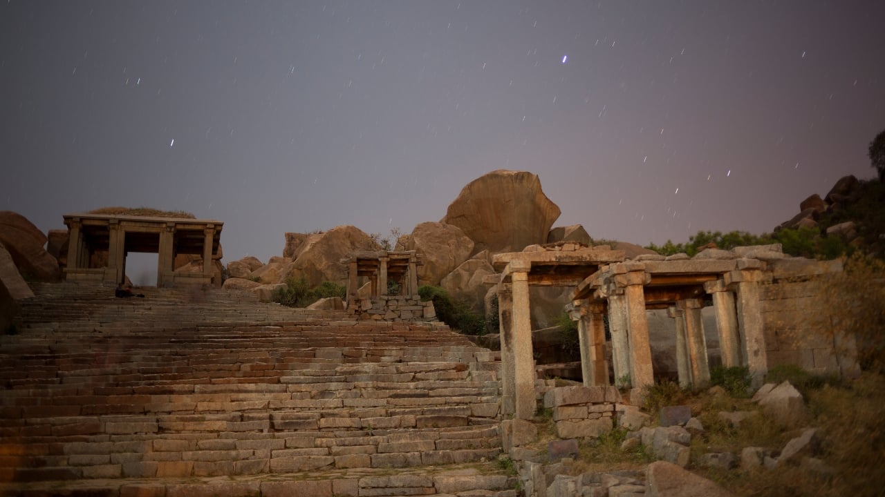 6. Hampi – Karnataka Hampi doesn't need the moon to feel ancient—but the moon certainly helps. With its boulder-strewn plains and forgotten temples, the ruined city feels transported from myth. Under a full moon, the granite takes on a soft sheen, and the stillness deepens. Walking through the remnants of empires in that light, one begins to question what is ruin and what is memory. (Image: Canva)