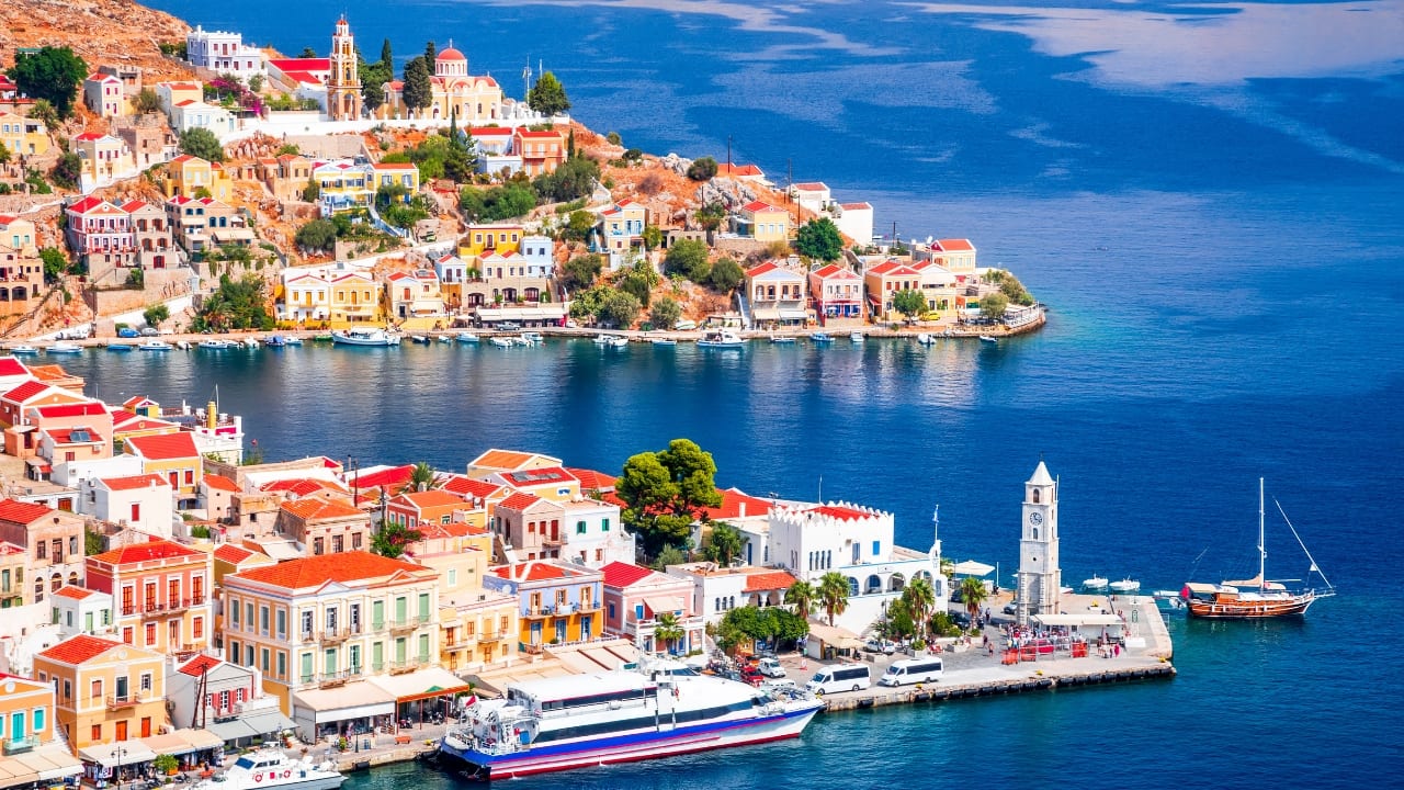 3. Symi – A Postcard Unsent Symi hovers just off Rhodes, too elegant to clamor for attention. Its pastel mansions rise tiered above the harbor, each a relic of a prosperous past, now softened by time. There are no grand monuments here, only subtle traces—a weathered staircase, a door ajar, a crumbling facade that tells more than any guidebook could. Time here does not pass; it circles. (Image: Canva)