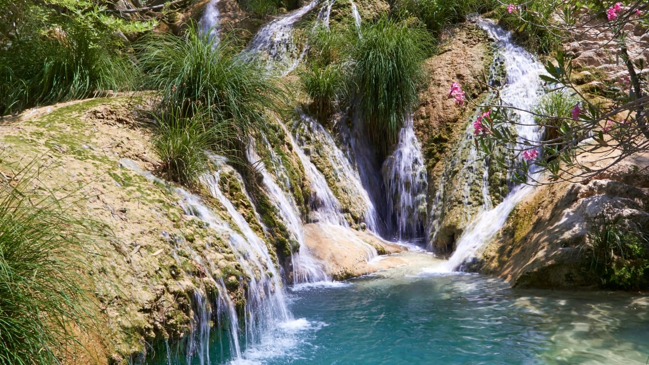 10. Polilimnio – Where Waterfalls Sing in Secret In the heart of Messinia, a path leads through olive groves and rustling reeds to Polilimnio—a chain of waterfalls so hidden they almost seem imagined. Pools collect at their base like mirrors laid flat. Locals know of it, speak of it quietly, visit on Sundays. It is not advertised, and that may be its greatest strength. (Image: Canva)