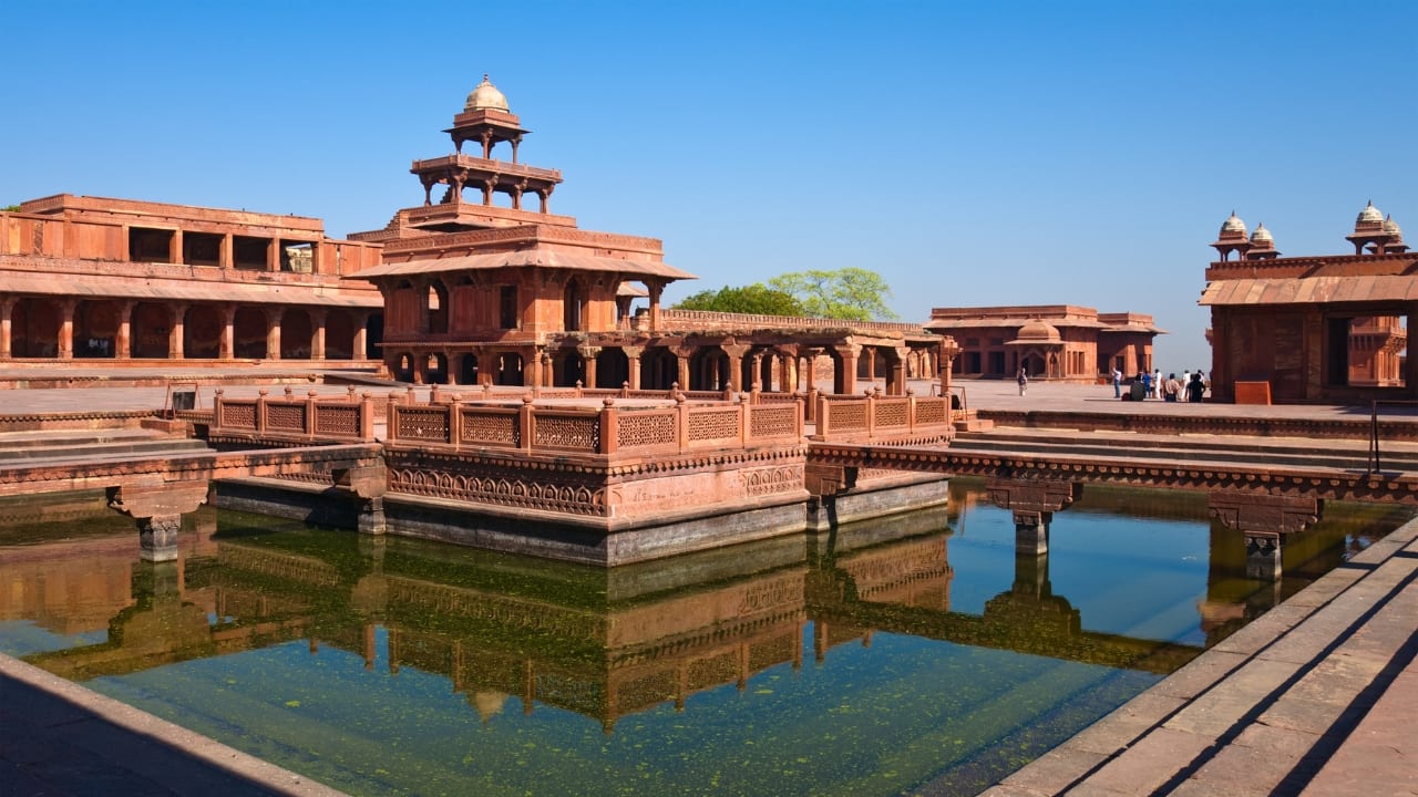 7. Fatehpur Sikri, Uttar Pradesh Akbar’s ghost capital stands not in ruin, but in pause. Red sandstone courtyards stretch wide, as if awaiting the return of a court that never came back. (Image: Canva)