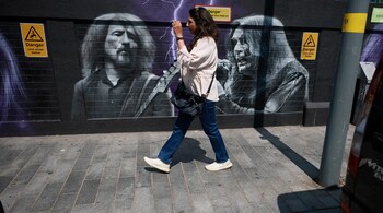 A woman walks past a mural painted in honour of rock band Black Sabbath ahead of their upcoming concert in Birmingham, Britain, July 2, 2025. REUTERS/Phil Noble/File Photo