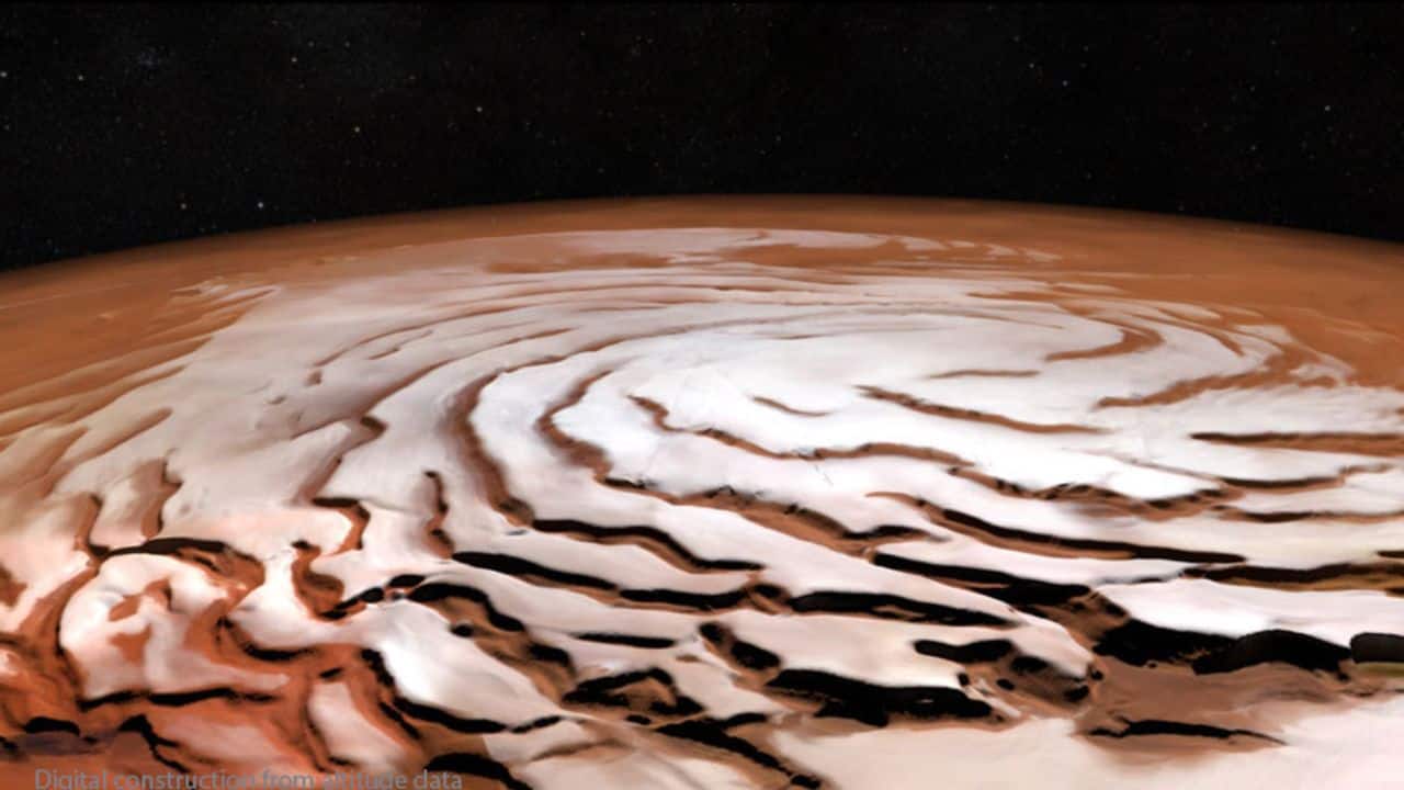 The Spiral North Pole of Mars: Mars’ North Pole forms spirals as winter winds swirl over its icy cap. Each year, a fresh carbon dioxide layer adds to the permanent water-ice, creating this striking pattern. (Image: NASA)