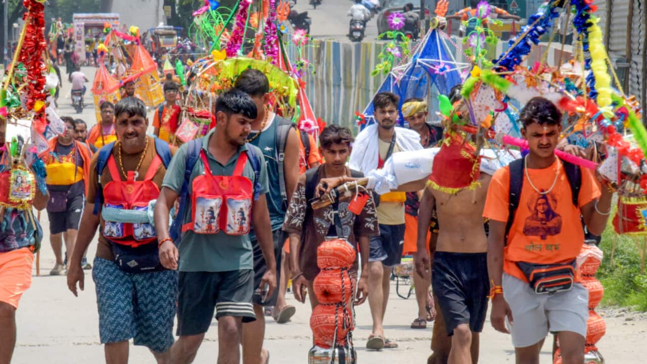 2. Haridwar, July 11: Devotees walk through Har Ki Pauri with Kawads on their shoulders, collecting Ganga Jal during the ongoing Kanwar Yatra. (PTI Photo)