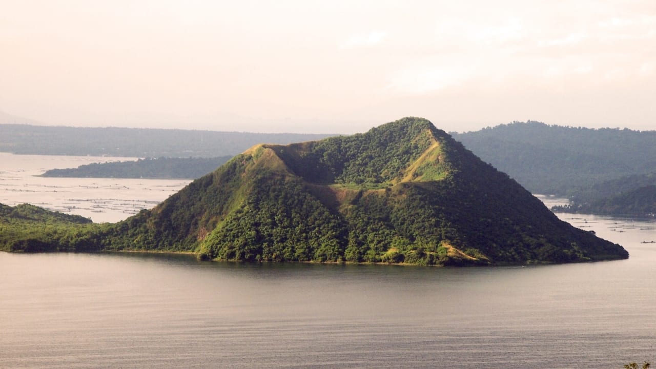 1. Taal Volcano Villages, Philippines Nestled around the deceptively tranquil waters of Lake Taal, these communities sit atop one of the most volatile volcanic systems in the world. Just 50 kilometres south of Manila, the Taal Volcano is capable of generating ash plumes, ground-shaking tremors, and volcanic tsunamis. Its 2020 eruption displaced more than 100,000 residents and coated cities in fine ash. Despite the risk, people continue to live here, drawn by fertile soil and proximity to economic centres. (Image: Canva) 1. Taal Volcano Villages, Philippines Nestled around the deceptively tranquil waters of Lake Taal, these communities sit atop one of the most volatile volcanic systems in the world. Just 50 kilometres south of Manila, the Taal Volcano is capable of generating ash plumes, ground-shaking tremors, and volcanic tsunamis. Its 2020 eruption displaced more than 100,000 residents and coated cities in fine ash. Despite the risk, people continue to live here, drawn by fertile soil and proximity to economic centres. (Image: Canva)