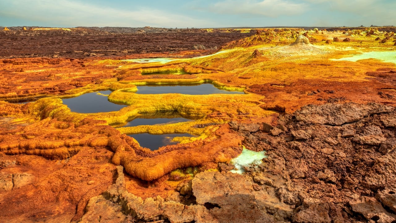 5. Dallol, Ethiopia Dallol, located in the Danakil Depression, holds the record for the highest average annual temperature ever recorded. With its sulphuric pools, neon mineral crusts, and geysers of toxic steam, it resembles a science fiction set more than a human habitat. Though now uninhabited, nomads and salt miners still pass through, navigating an area where rainfall is virtually nonexistent and the air can scald. (Image: Canva) 5. Dallol, Ethiopia Dallol, located in the Danakil Depression, holds the record for the highest average annual temperature ever recorded. With its sulphuric pools, neon mineral crusts, and geysers of toxic steam, it resembles a science fiction set more than a human habitat. Though now uninhabited, nomads and salt miners still pass through, navigating an area where rainfall is virtually nonexistent and the air can scald. (Image: Canva)