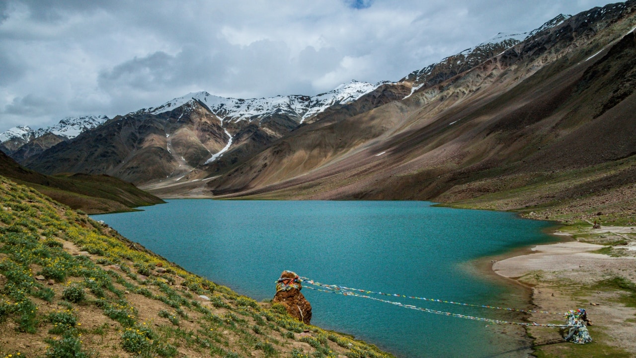 5. Chandratal Lake, Himachal Pradesh Set amidst the stark terrain of Spiti, Chandratal—literally “Moon Lake”—enchants with its curved form and translucent waters. During twilight, when the sky bleeds orange and pink, the lake becomes a mirrored arc that holds the entire horizon within its crescent. (Image: Canva)