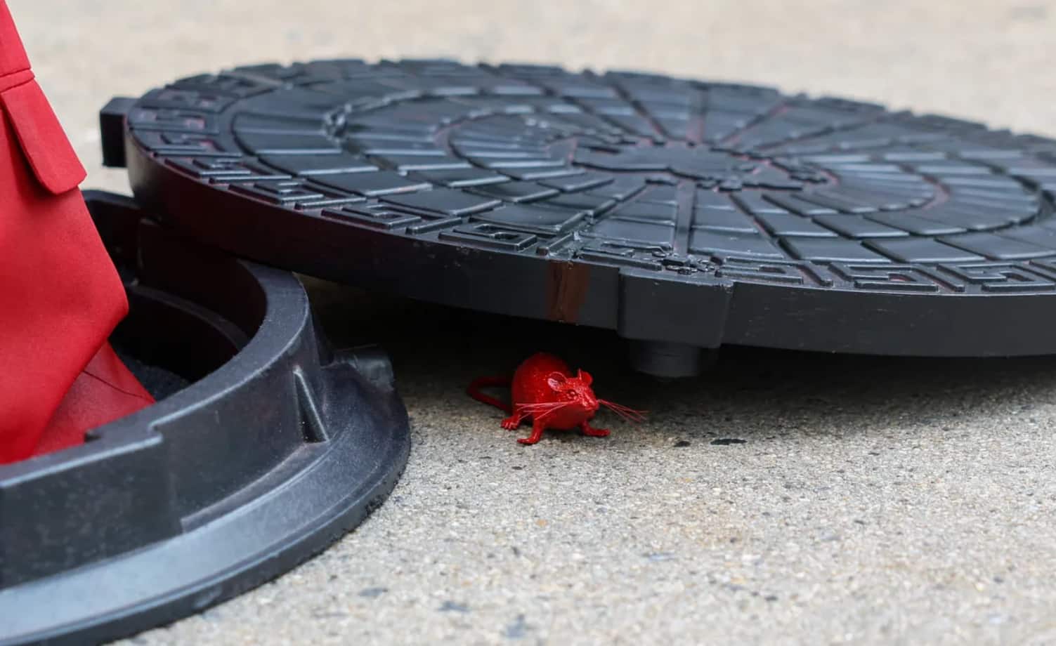 Beneath the manhole lid, a small red rat peered out - part of the sculpture's message and symbolism. (Image: Reuters) 