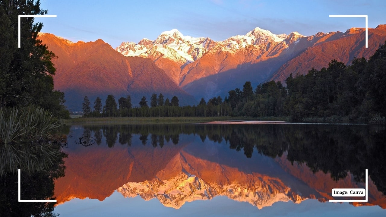 11. Lake Matheson, New Zealand Lake Matheson is renowned for its perfect mirror-like reflections of Mount Cook and Mount Tasman. Photographers flock here at dawn to capture the serene interplay of light and shadow on the still waters, creating nature’s own masterpiece. (Image: Canva)