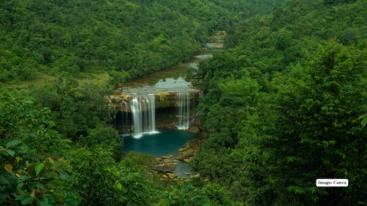 5. Krang Suri Falls, Meghalaya – An Aquamarine Dream Hidden within the Jaintia Hills, Krang Suri Falls is one of Meghalaya’s most surreal sights. The aquamarine waters, set against forested cliffs, form a natural amphitheatre of mist and light. Reached via a scenic forest trek, it’s a photographer’s delight and a cultural gateway to the Pnar community’s hospitality. (Image: Canva)