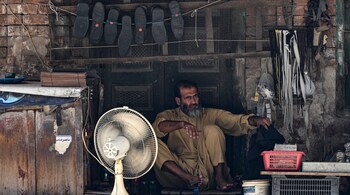 File Photo - A cobbler waits for customers at his stall in Rawalpindi on June 9, 2025, ahead of the state budget. (Photo by Farooq NAEEM / AFP)