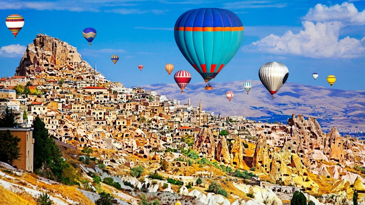 2. Cappadocia, Turkey Famous for its whimsical “fairy chimneys” and ancient cave homes, Cappadocia is best seen from above in a hot-air balloon. At sunrise, hundreds of colorful balloons float over the lunar-like landscape, creating a dreamlike scene that feels like a fantasy film. (Image: Canva)