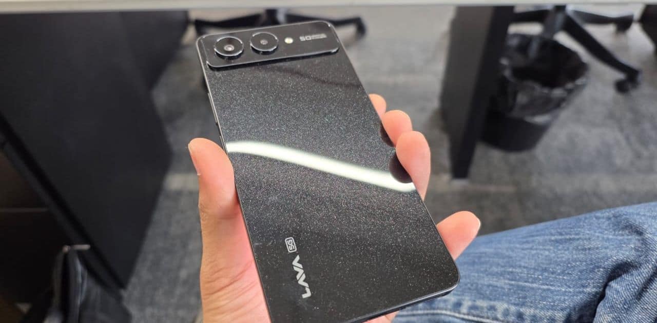 Lava Blaze AMOLED 2 Design The Blaze AMOLED 2 follows Lava’s recent design language with a flat-edged frame, a large rear camera module, and clean back finishes in Feather White and Midnight Black. The white variant reflects light subtly, avoiding overly glossy patterns while still looking distinctive. The phone feels surprisingly light at 174 grams given its 5000mAh battery capacity, and at 7.55mm thick, it’s comfortable for one-handed use for longer stretches. The build uses a polycarbonate frame and back panel, which is expected at this price, but the finish helps avoid it feeling overly cheap. Lava Blaze AMOLED 2 Design The Blaze AMOLED 2 follows Lava’s recent design language with a flat-edged frame, a large rear camera module, and clean back finishes in Feather White and Midnight Black. The white variant reflects light subtly, avoiding overly glossy patterns while still looking distinctive. The phone feels surprisingly light at 174 grams given its 5000mAh battery capacity, and at 7.55mm thick, it’s comfortable for one-handed use for longer stretches. The build uses a polycarbonate frame and back panel, which is expected at this price, but the finish helps avoid it feeling overly cheap.