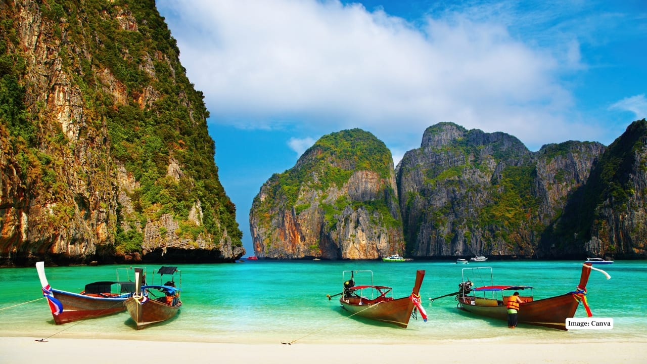 6. Maya Bay, Koh Phi Phi Ley (Thailand) Enclosed by steep limestone cliffs, Maya Bay features pristine white sand and crystal-clear turquoise waters. Famously featured in the film The Beach, this cinematic spot draws travelers from across the globe. (Image: Canva)