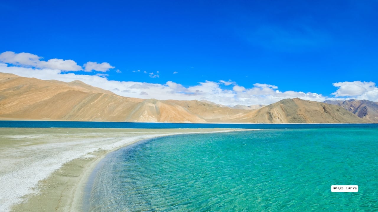 1. Pangong Tso: The Iconic Blue Wonder No trip to Ladakh is complete without a visit to Pangong Tso. Famous for its striking blue waters that shift shades with the sunlight, this high-altitude lake stretches across India and China. Surrounded by barren mountains and vast open skies, Pangong Tso offers a surreal backdrop perfect for photography, camping, and soaking in the unique Himalayan serenity. (Image: canva)