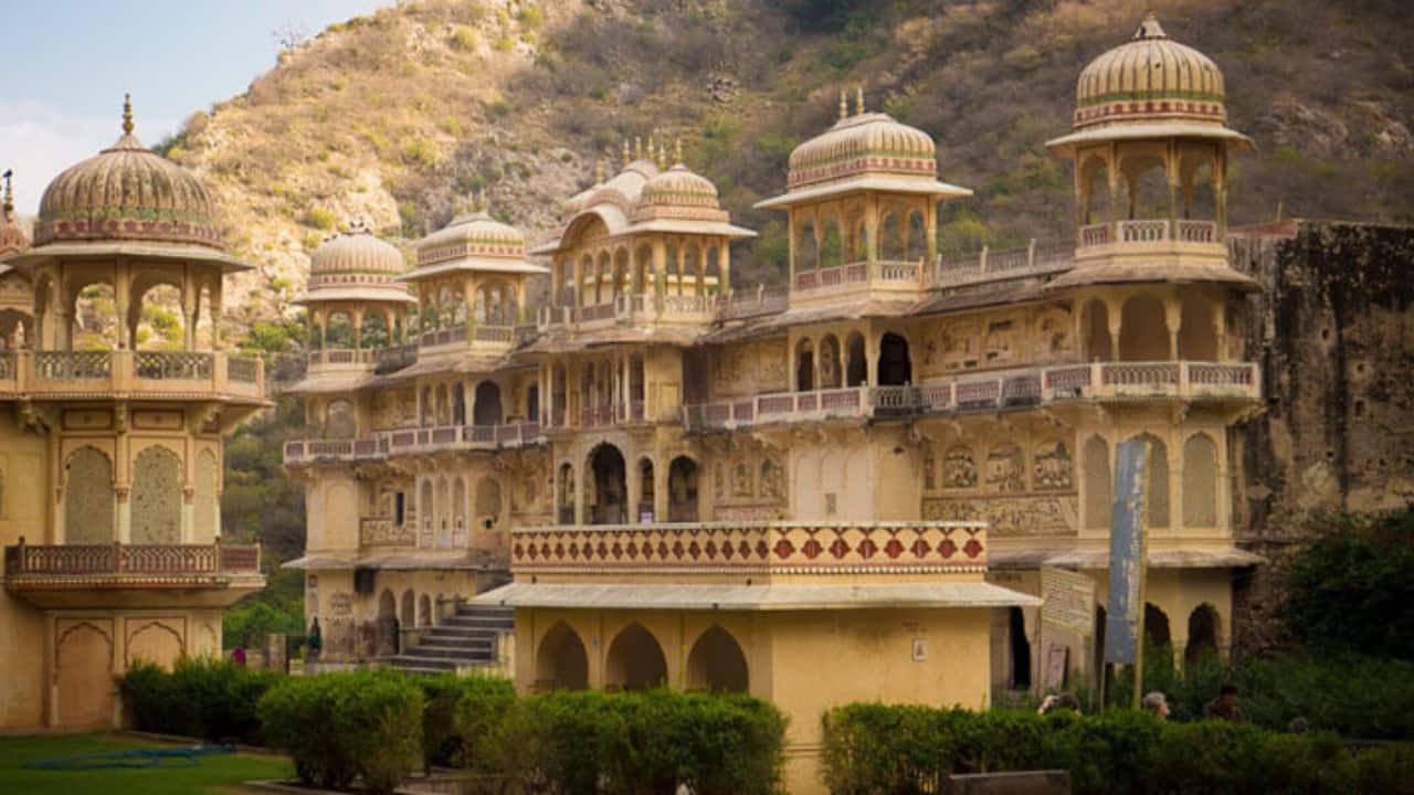 Hiking Trails and Sunset Views Adventure-seekers often hike to Galta Ji. The trail begins at the end of Suraj Pol Bazar Road and takes 30–45 minutes, passing through a striking pink stone archway and the Sun Temple, a spot famous for its panoramic sunsets. From here, you can take in sweeping views of Jaipur’s skyline and fortifications glowing under the fading Rajasthani sun. (Image: Jaipur Tourism)