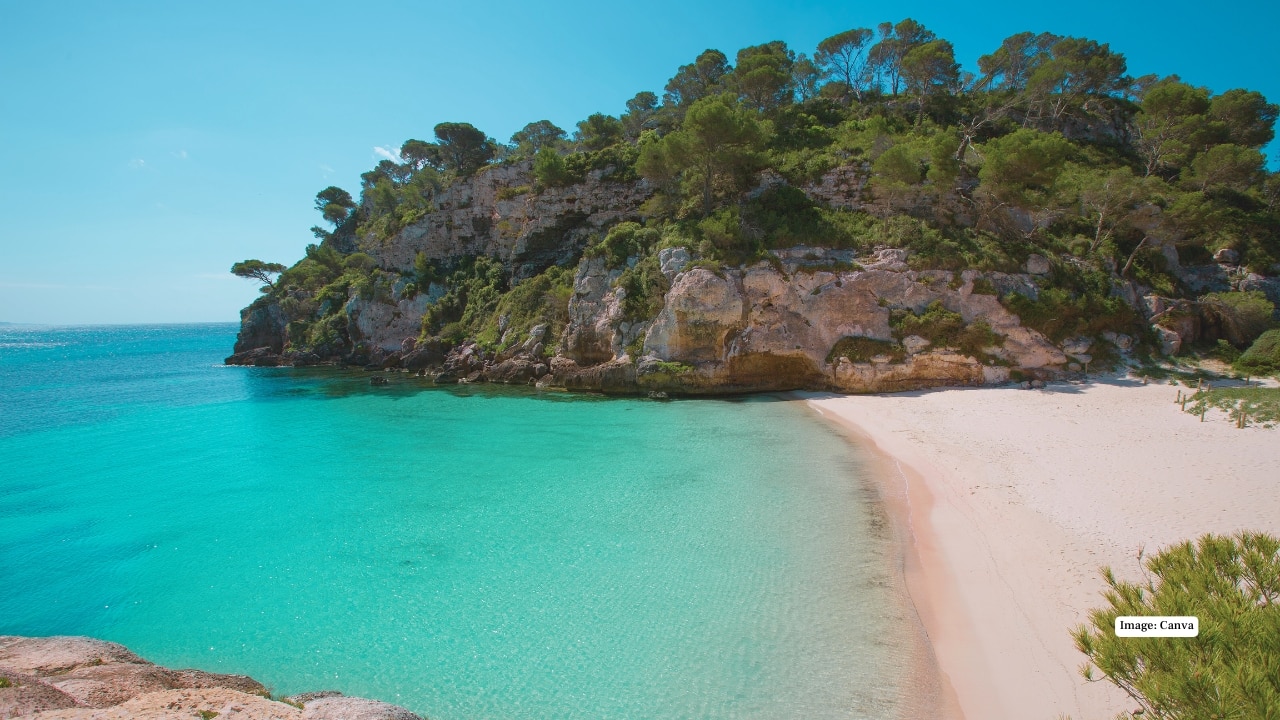 6. Cala Macarelleta, Menorca Nestled on Spain’s Balearic island of Menorca, Cala Macarelleta is a tiny cove with aquamarine waters framed by limestone cliffs and pine trees. A postcard Mediterranean hideaway, it’s perfect for swimming, sunbathing, and solitude. (Image: canva)