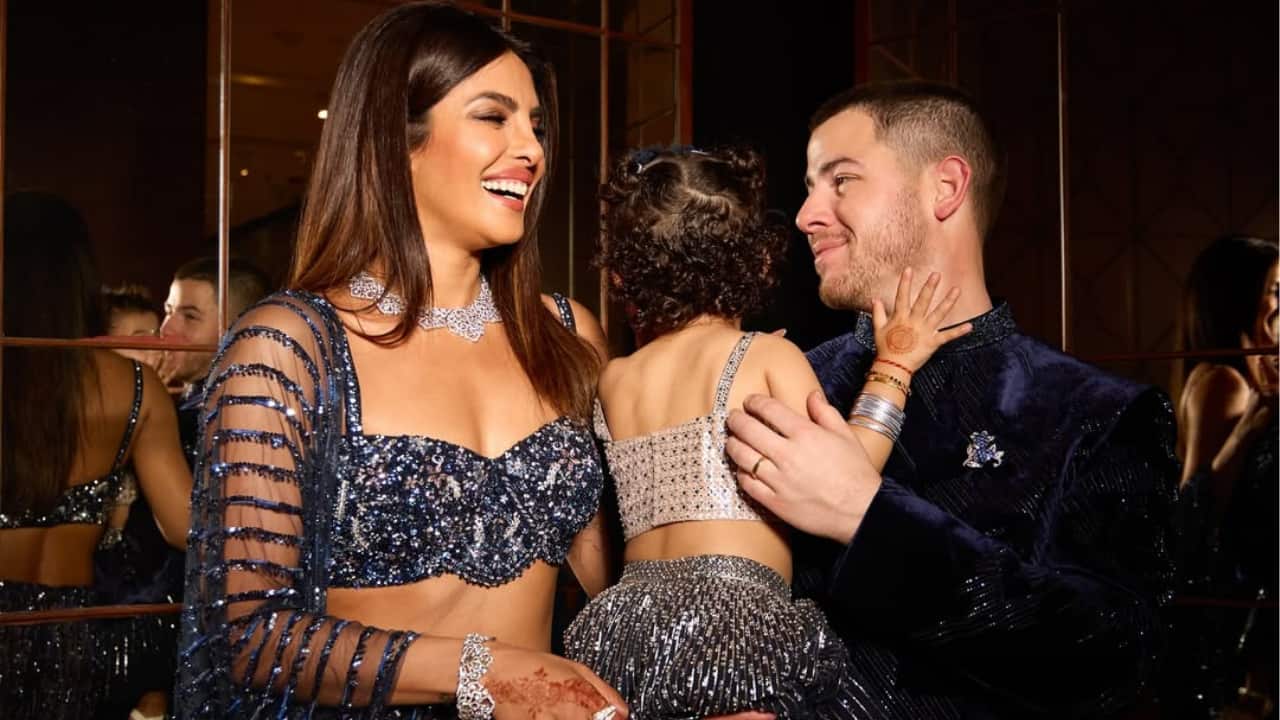 A Glistening Family Moment  Nick Jonas and Priyanka Chopra are beaming with happiness as they celebrate a milestone with their daughter, Malti. The three of them share a touching moment while wearing coordinated, glittering traditional attire. Cradled in Nick's arms, Malti completes this idyllic depiction of love, custom, and treasured family time.
