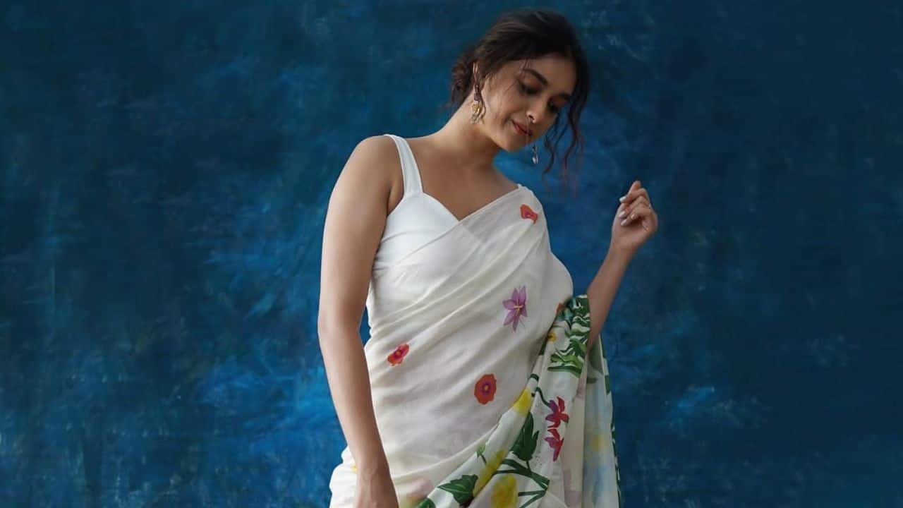 Keerthy’s ethnic background inspires calm beginnings Keerthy looks simple and sober as she wore a white cotton saree with floral design prints, paired with deep-necked blouse. The actress’s styled bun with minimal accessories complemented her Navratri look