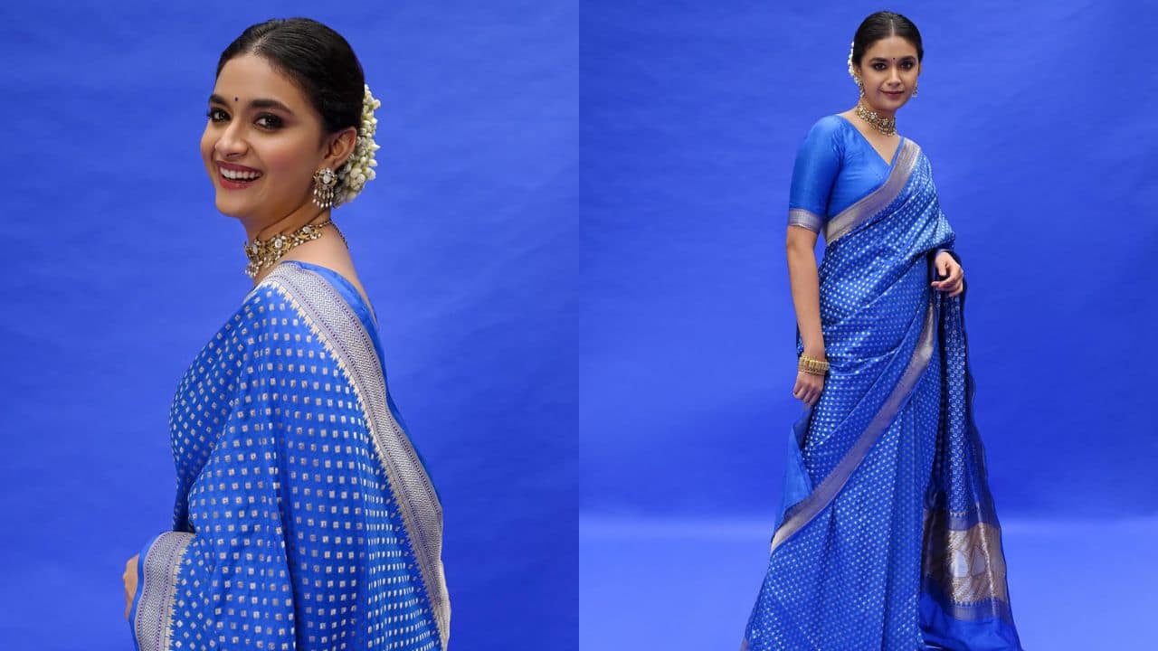 Elegant Blue, Ethnic Hues Keerthy looked beautiful in the blue Banarasi saree with silver and a beautifully decorated pallu paired with a stylish haf-sleeve blouse with back cutout. The traditional jewelry including a necklace and a neat but completed the actress’s Navratri puja look